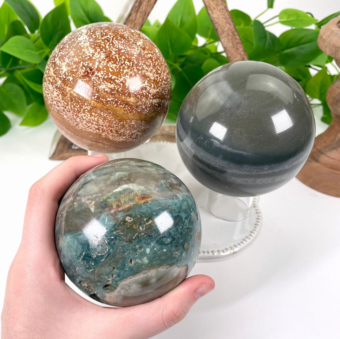 all three ocean jasper polished sphere weight options on display for size comparison with one in hand for reference
