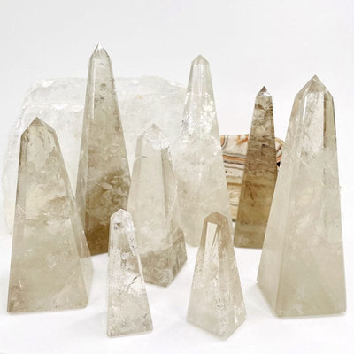 multiple smokey quartz obelisk displayed to show the differences in the sizes and color shades 