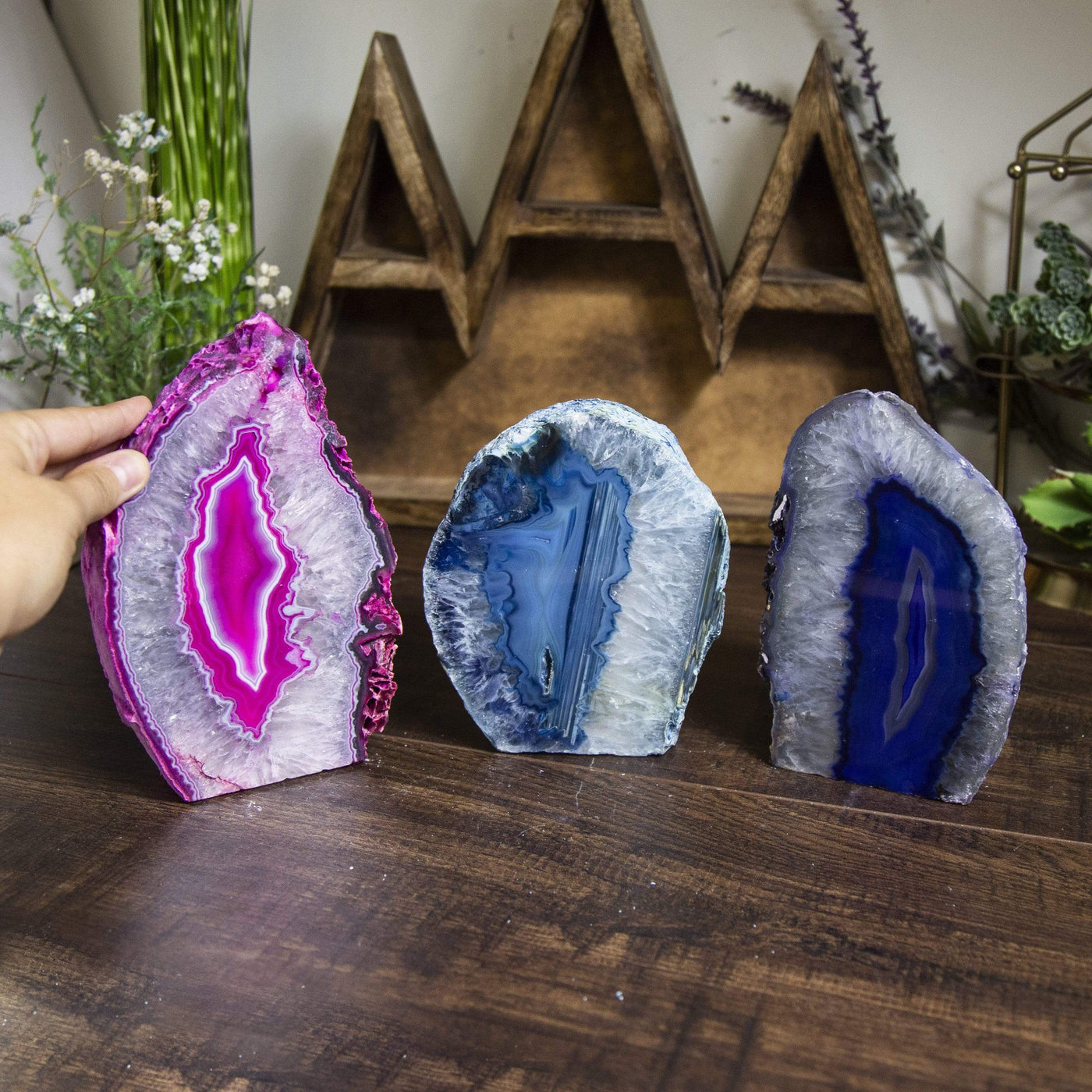 Three agate lamps on a dark surface with a hand next to a lamp for size reference within an alter.