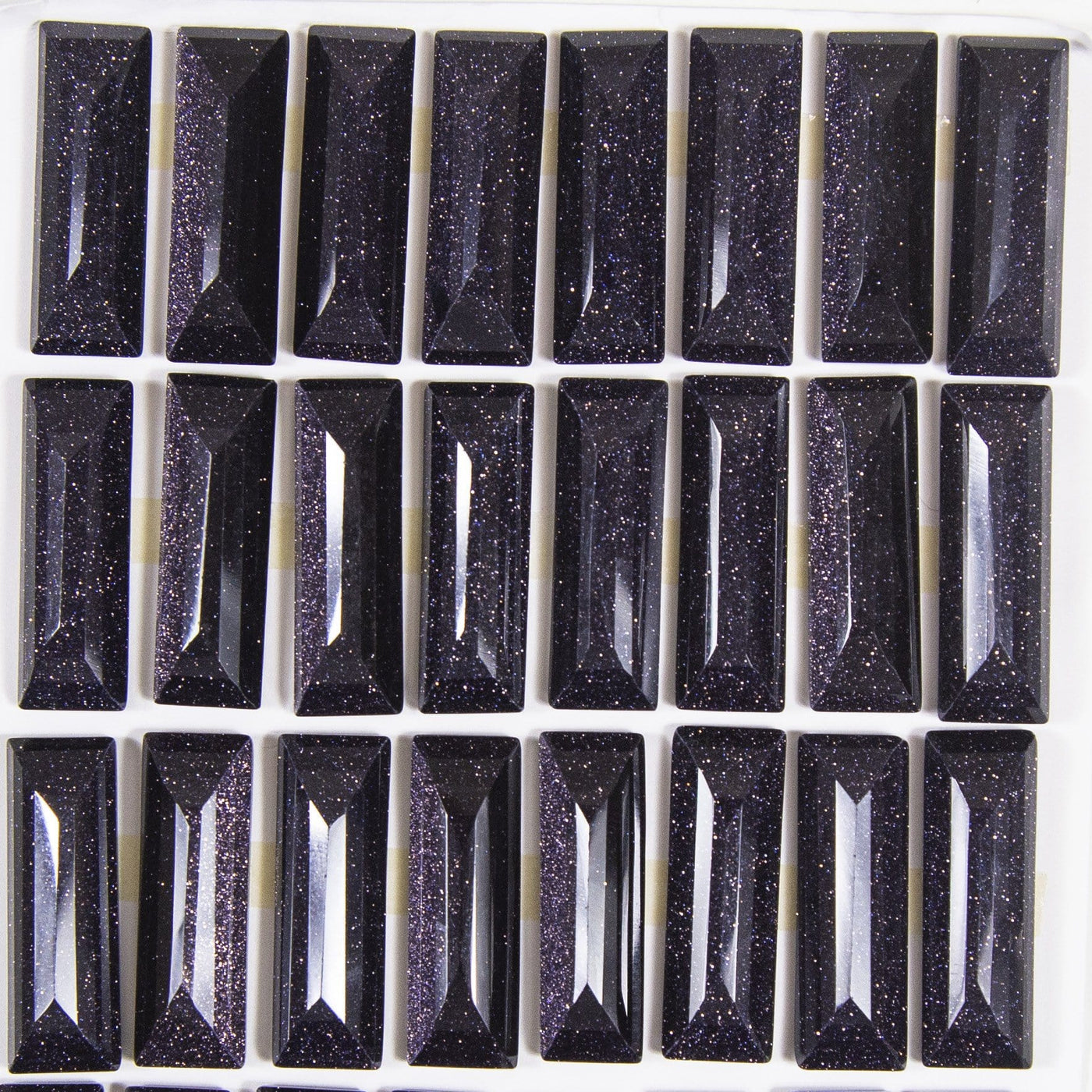 multiple blue goldstone faceted cabochons displayed to show the slight differences 