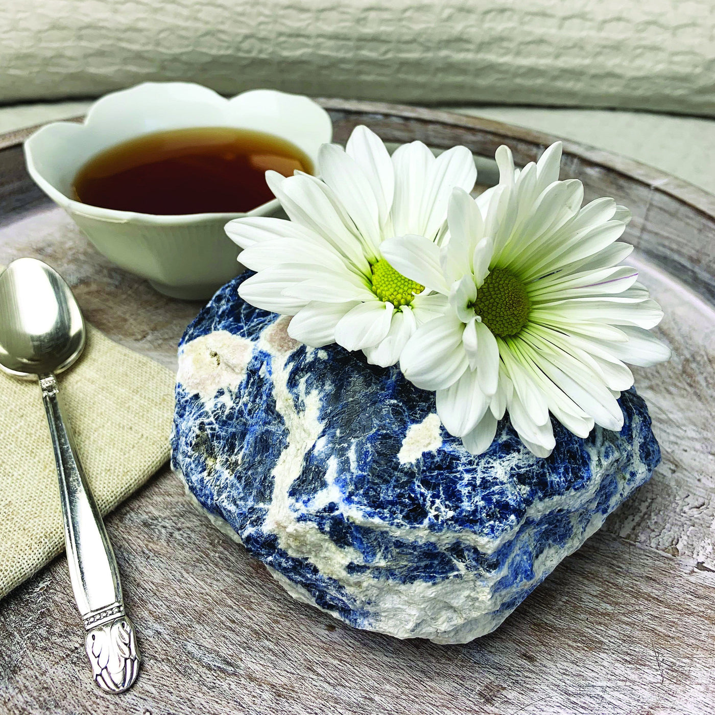 Sodalite Candle Holder displayed on tray with flowers and coffee to show the beauty of the natural blue and white stone