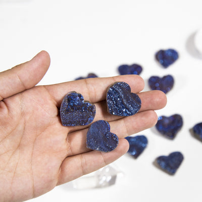 3 different sizes of Blue Titanium Hearts in hand for size reference