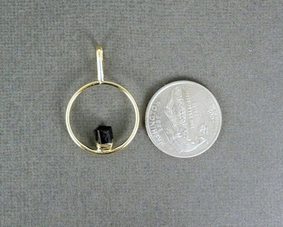 tourmaline pendant next to a quarter for size reference