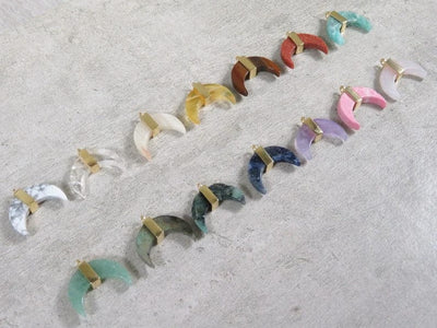 various crescent pendants lined up on gray background