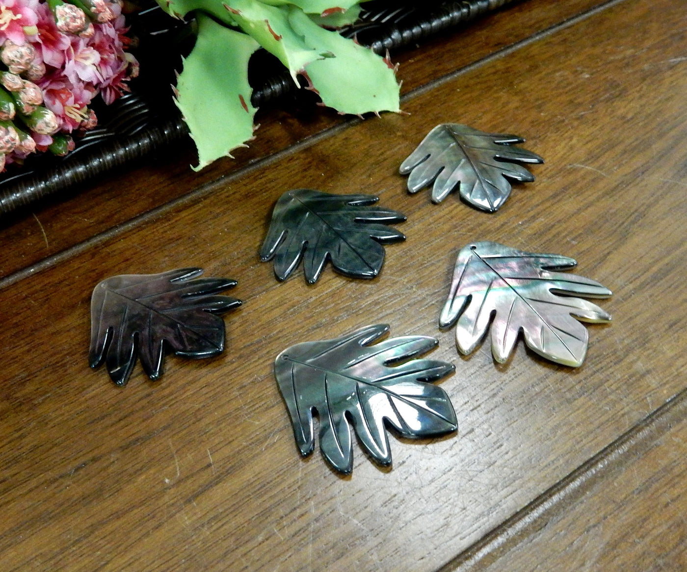 Abalone - Black Mother Of Pearl Leaf Bead - 5 on a table