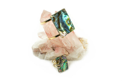 1 Abalone Geometric Cuff in Gold Electroplate and 1 Abalone geometric ring in Gold on display with a crystal.