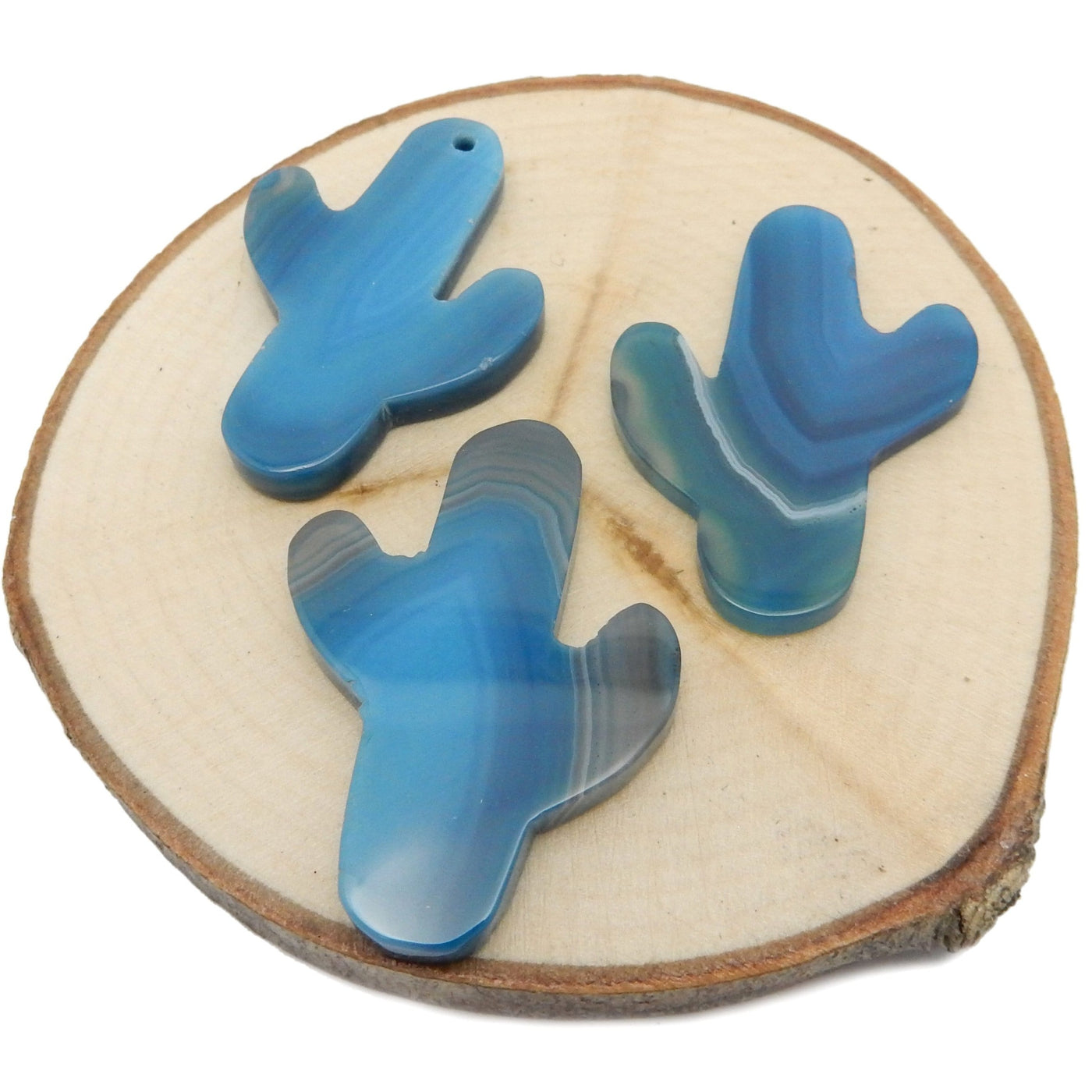 This picture is showing 3 of our blue cactus agates, being displayed on a wooden platform.