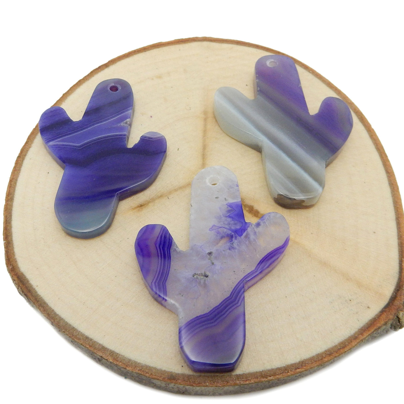 This picture is showing 3 of our purple cactus agates, being displayed on a wooden platform.