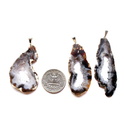 Three Agate Geode Natural Druzy Pendants next to a quarter for size reference.