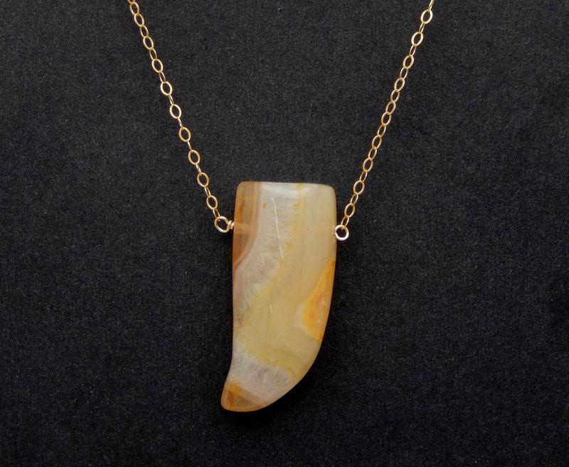 An agate horn with a chain displayed on a dark colored background.