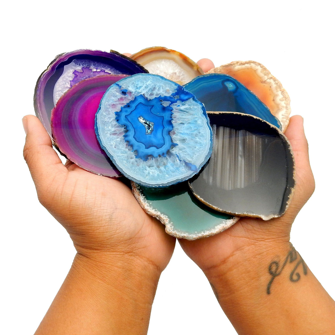 This picture is showing all the variety of colors we have available for our size 2 agate slices. They are also being displayed in hands.  