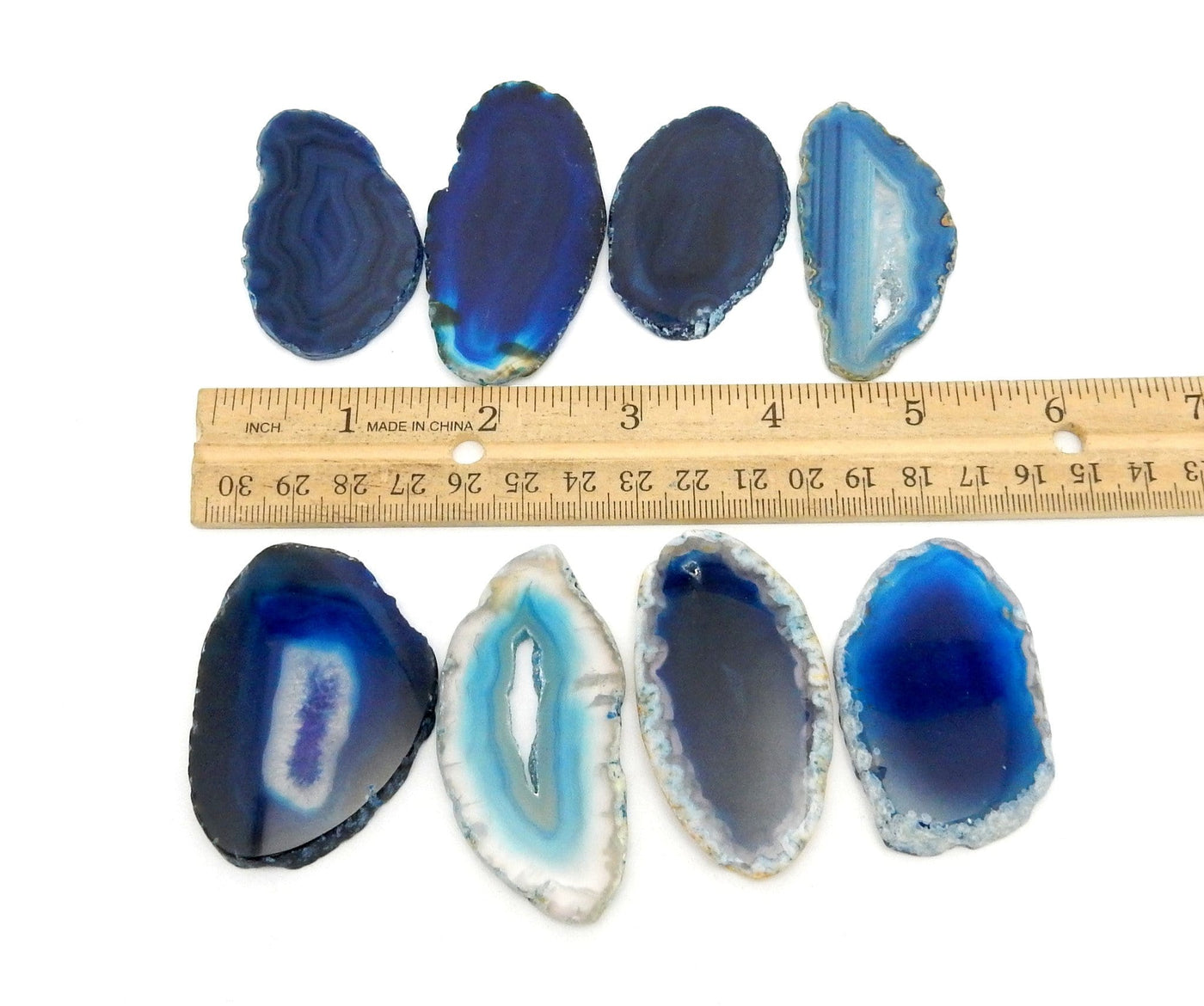 Picture of Blue agate slices on white back ground, next to ruler for size reference.
