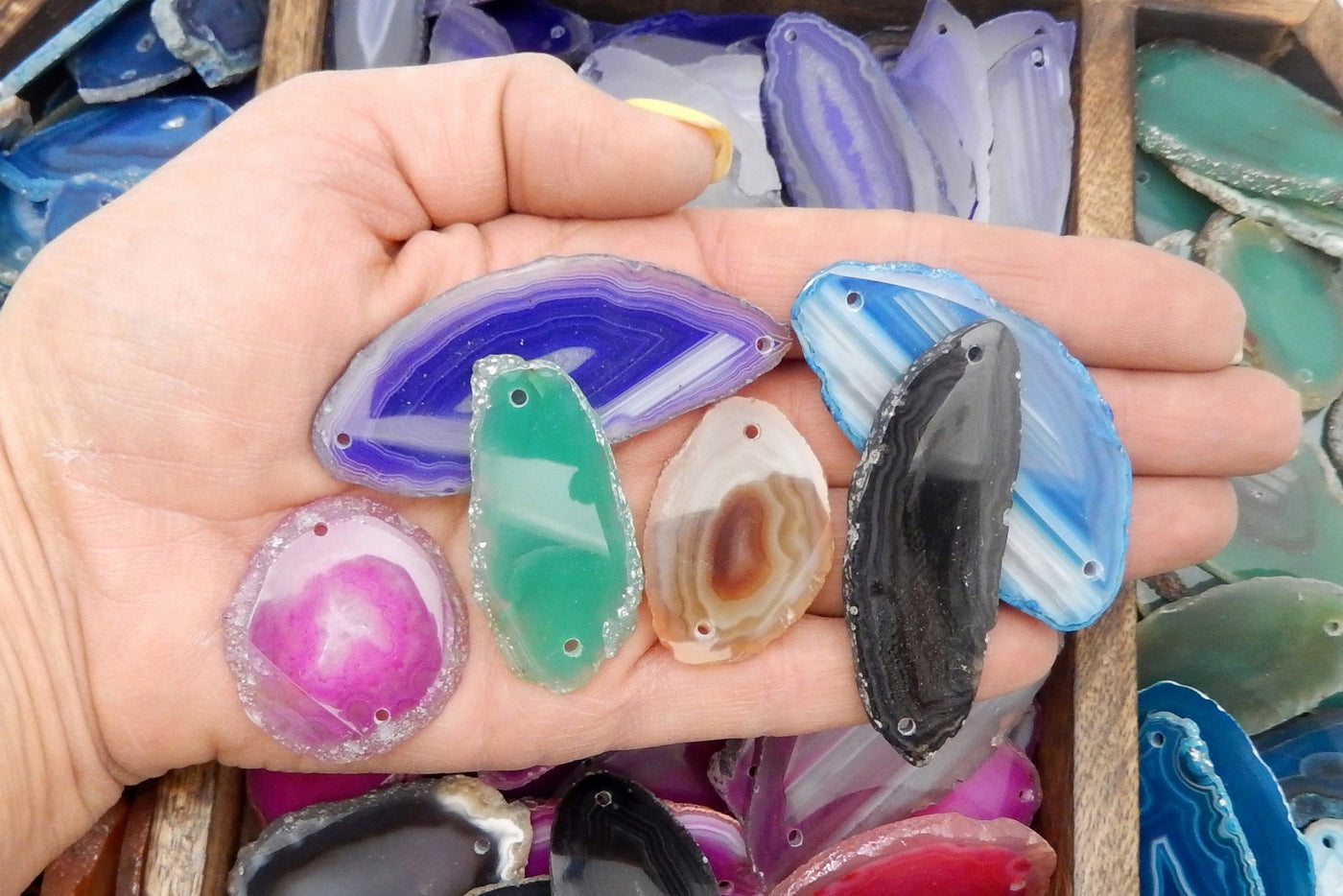 Agates slices are being held for size reference. 