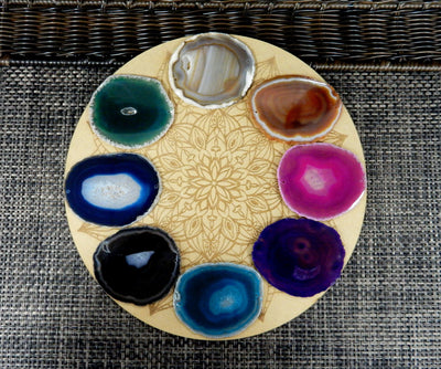Multi color agate slices being displayed on a wooden grid.