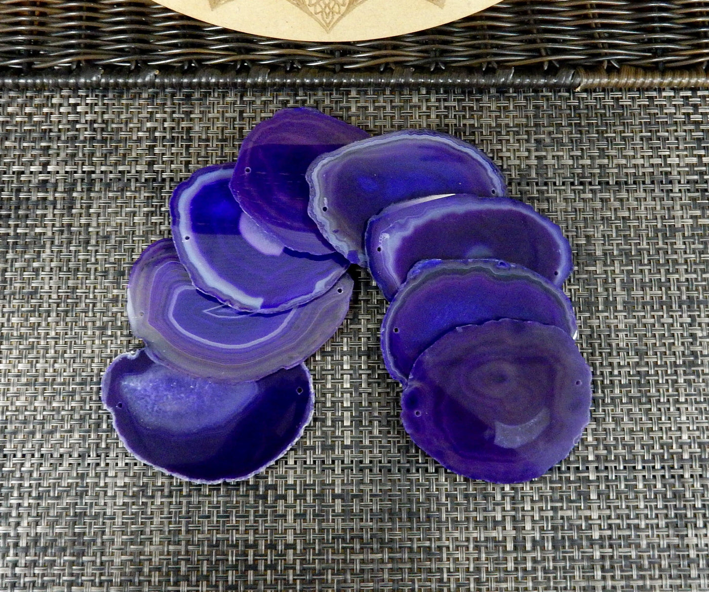 purple agate slices being displayed on a dark brown back ground.