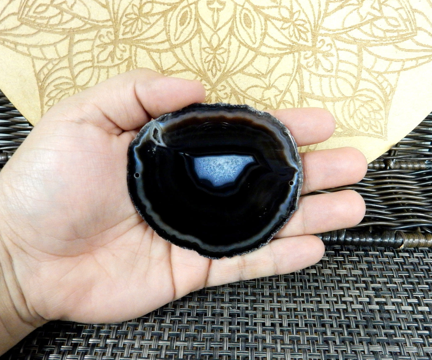 Black agate slice is being held for size reference.