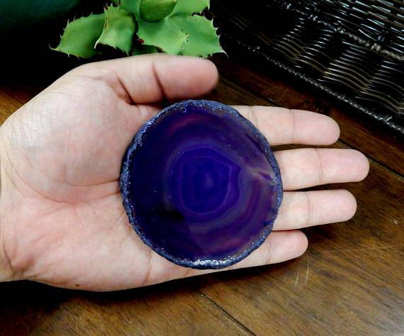 Picture of single purple agate slice being held for size reference.