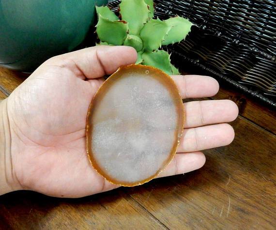 Single natural agate slice being held for size reference.