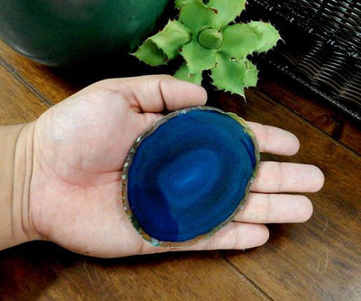 Single blue agate slice being held for size reference.