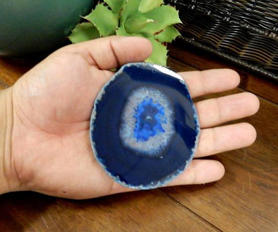 single blue agate slice being held for size reference.