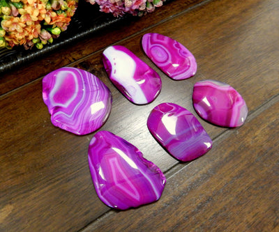 Side Angle 6 Pink FreeForm Agate Slices with Polished Edge on Wooden Background.