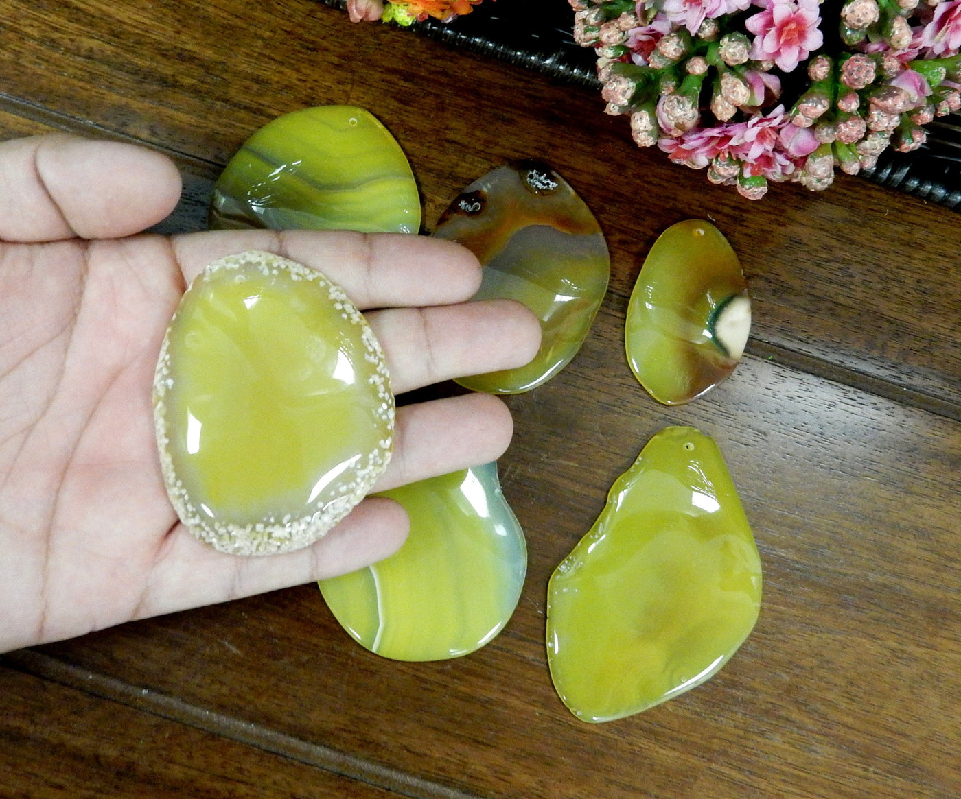  Yellow Freeform Agate Slice with Polished Edge In Hand on Wooden Background.