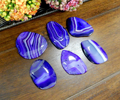 Close Up of 6 Purple FreeForm Agate Slices with Polished Edge on Wooden Background.