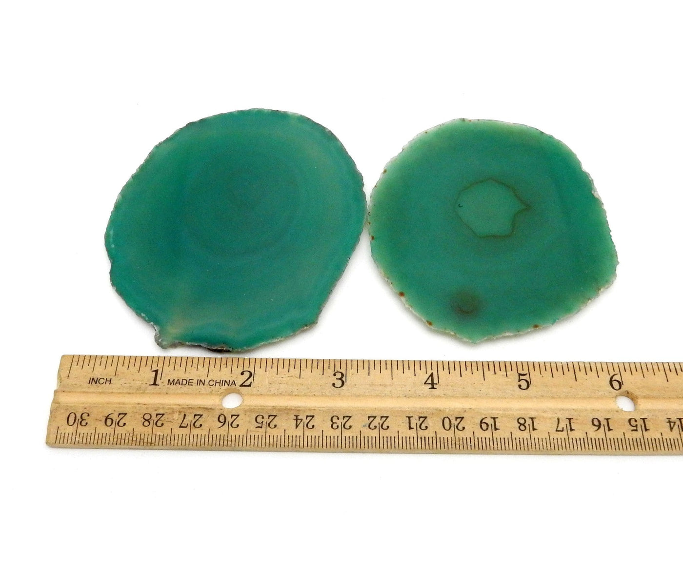 green agate slices next to a ruler for size reference 