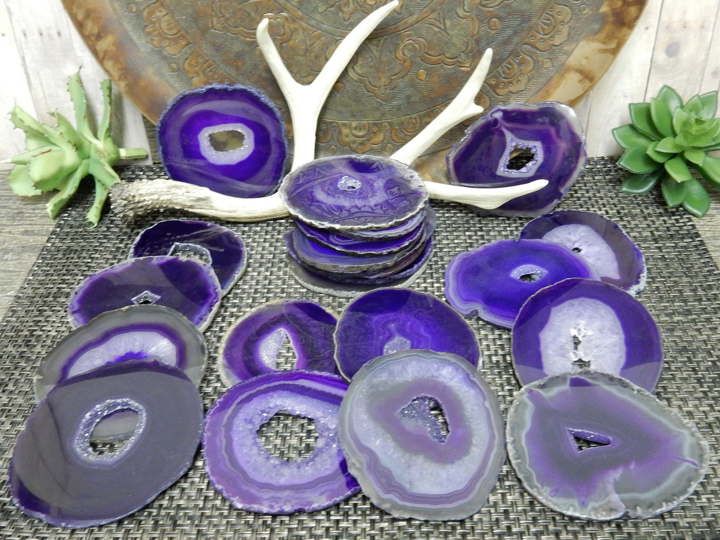 Many druzy purple agates displayed on a mat to show the difference in colors and shapes . 