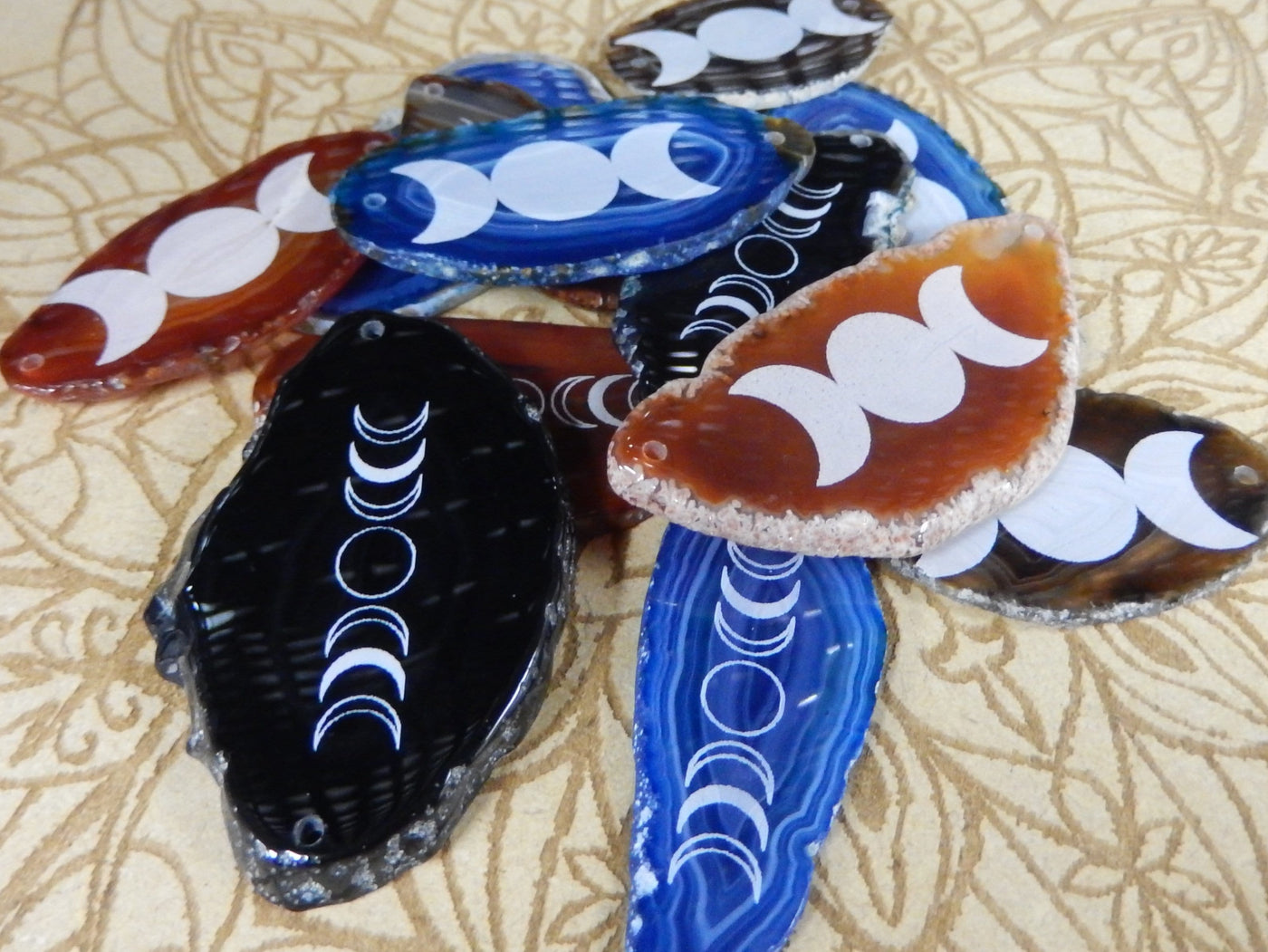 Picture of our blue, red/ orange and black agate slices double drilled, being displayed on table.