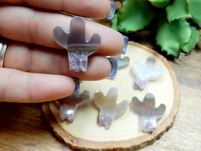 Hand holding up amethyst cactus cabochon with others in the background