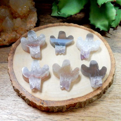 6 amethyst cactus cabochons on wooden platter with plants in the background