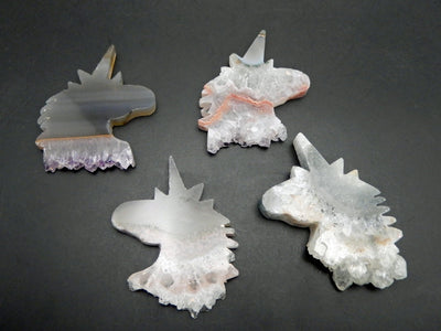 multiple Amethyst Stalactite Unicorn Shaped Cabochons displayed on gray background to show various colors and formation between each unicorn