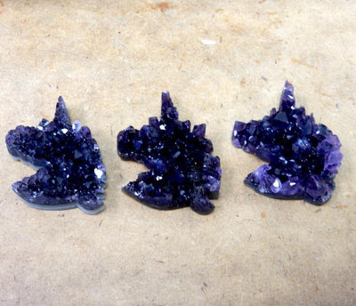 3 amethyst unicorn cabochons on brown background