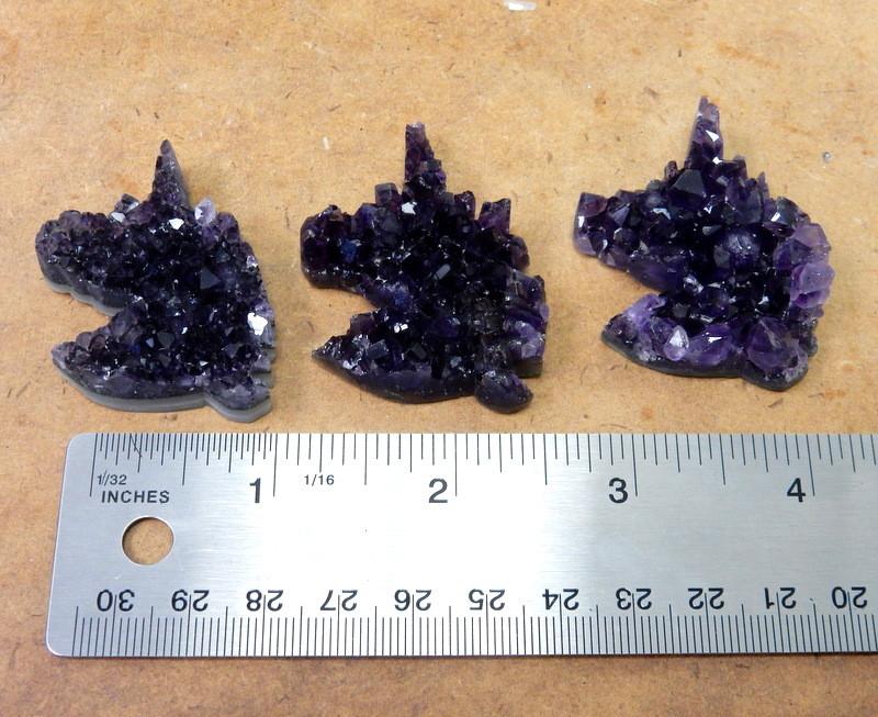 3 amethyst unicorn cabochons next to a ruler for size reference