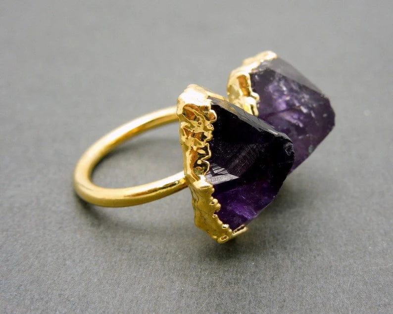 Side view of Amethyst double point adjustable gold plated ring on a grey background.