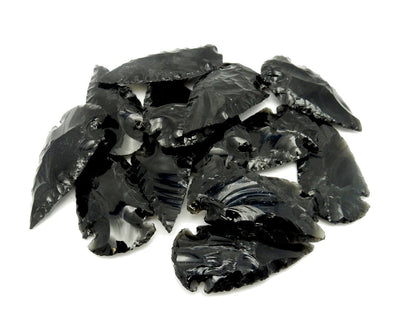 a stack of black obsidian arrowheads on a white background.