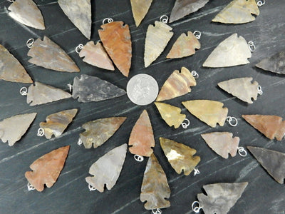 arrowhead pendants surrounding a quarter for size reference