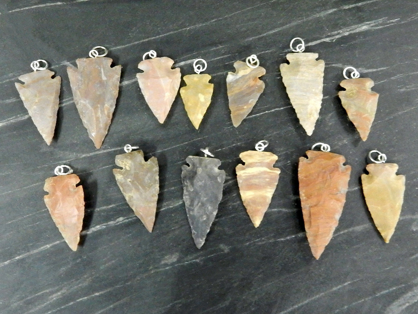 arrowhead pendants lined up on black background