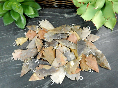 pile of arrowhead pendants with decorations in the background