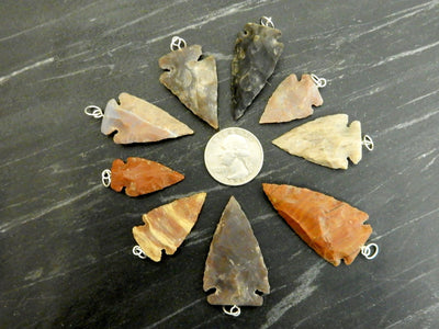 arrowhead pendants surrounding a quarter for size reference