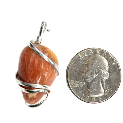Aventurine Silver Tone Spiral Tumbled Peach Aventurine Pendant next to  a quarter for size reference
