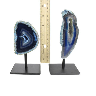 Two front facing agate geodes on a metal base next to a ruler for size reference.