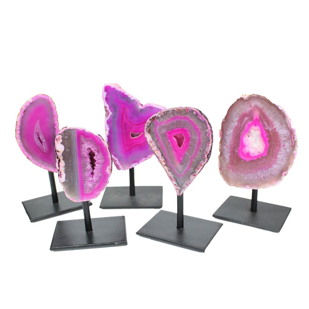 Five pink front facing agate geodes on a metal base with a white background.
