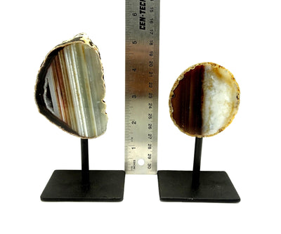 Two front facing agate geodes on a metal base next to a ruler for size reference.