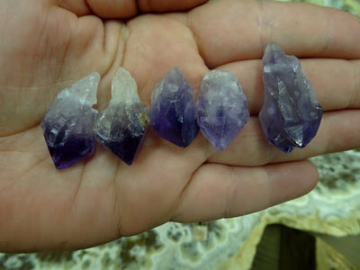 Assorted amethyst points in a hand.