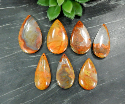 7 Drilled Red Chinese Agate Wide Long Teardrop Shaped Top Drilled Bead on Gray Background.