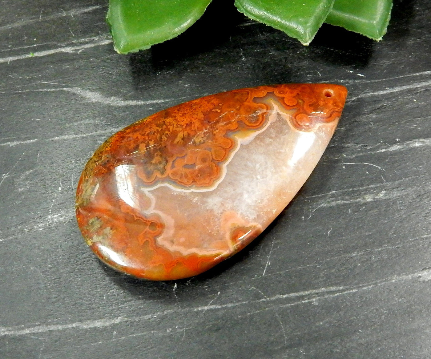 Close Up of Drilled Red Chinese Agate Wide Long Teardrop Shaped Top Drilled Bead on Gray Background.