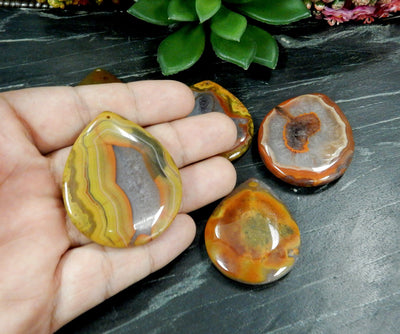 Hand holding up Red Chinese Agate Wide Teardrop Shaped Top Drilled Bead with others in the background