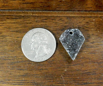 Druzy Diamond Drilled Cabochon, 1 laid on a table shown from top view next to quarter for size reference